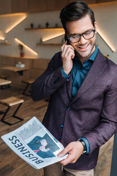 businessman with newspaper talking on smartphone - Foto, afbeelding