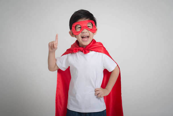 Porträt eines asiatischen Kindes im Superheldenkostüm auf grauem Hintergrund - Foto, Bild