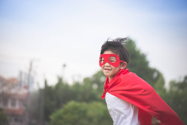 Азиатский ребенок в костюме супергероя играет в парке
 - Фото, изображение