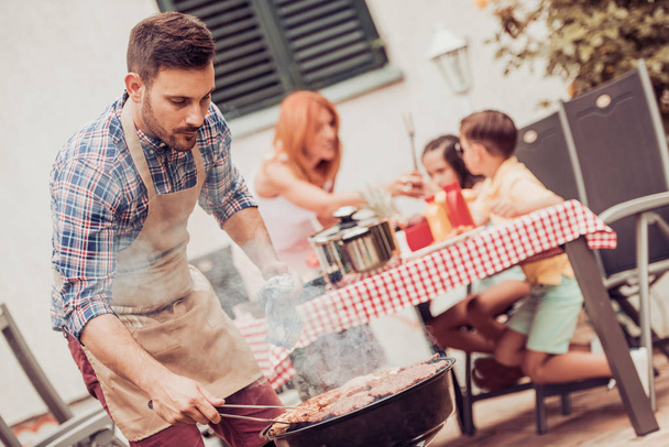 Happy family having barbecue - Foto, afbeelding