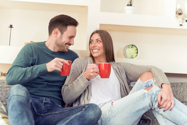 Ζευγάρι κάθεται στον καναπέ και πίνει καφέ - Φωτογραφία, εικόνα