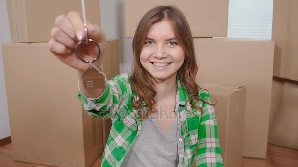 Szczęśliwa młoda kobieta z kluczem z nowego mieszkania - Materiał filmowy, wideo