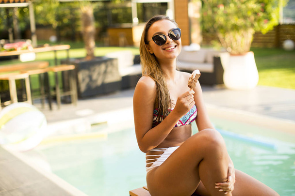 Красивая молодая женщина с мороженым у бассейна
 - Фото, изображение