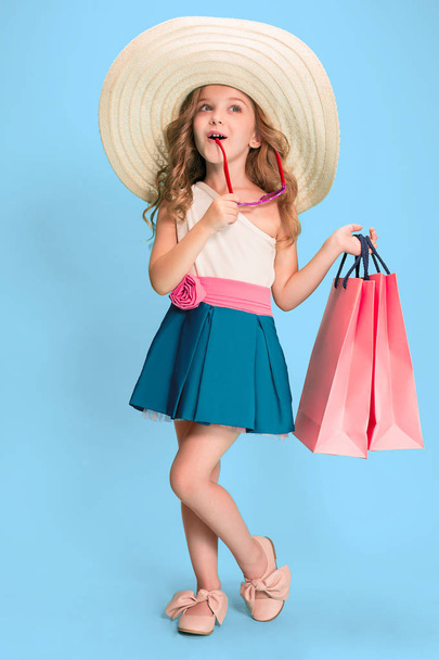The cute little caucasian brunette girl in dress holding shopping bags - Foto, Imagem