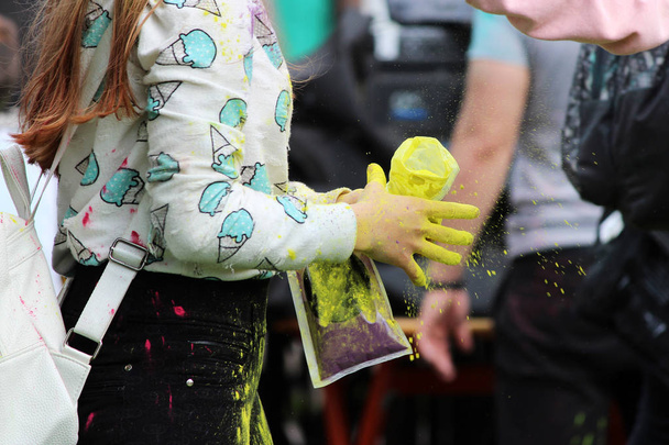 Chica derrama pintura en polvo amarillo seco en su amigo en el festival de Holi festival en Gatchina, Rusia
. - Foto, imagen