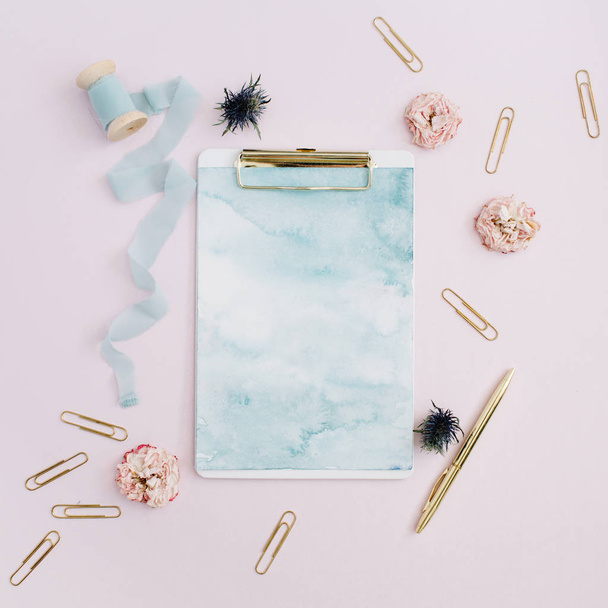 Klembord, rose toppen, blauwe lint, gouden pen en clips - Foto, afbeelding