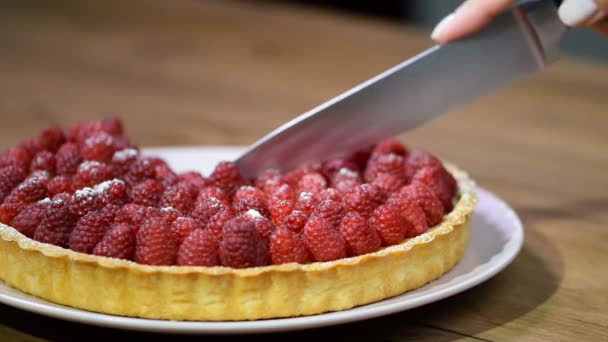 Woman's hand cut with a kitchen knife tart with raspberries - Footage, Video