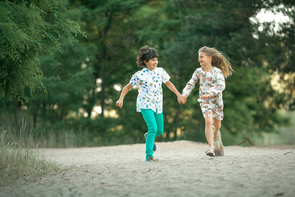Little girl and boy are running in forest and holding hands.  - Foto, afbeelding