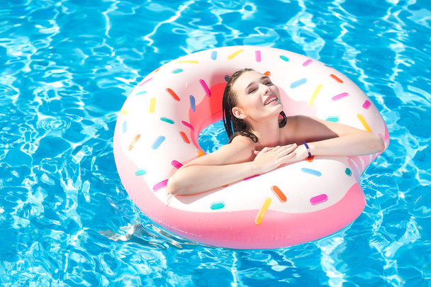 Fiatal kaukázusi fehér gyönyörű nő pihentető medencével várja vendégeit. Szexi lány úszás a gumi gyűrű, mosolyogva, és a szórakozás, az aquapark. Nyári pihenés és az aktív pihenés koncepció. - Fotó, kép