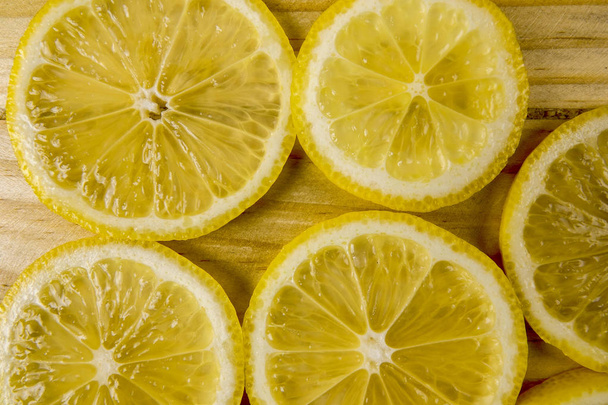 Čerstvé citrónové řezy na dřevěné pozadí. - Fotografie, Obrázek