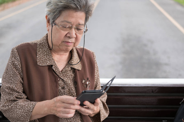 aasialainen vanhempi nainen jolla mobiili älypuhelin bussissa. iäkkäät potilaat
 - Valokuva, kuva