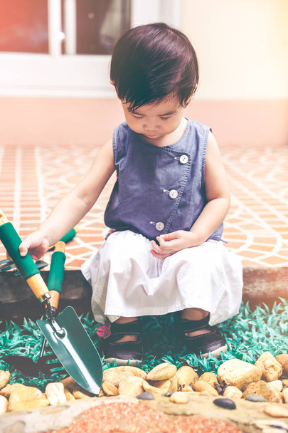 Niño asiático con equipo de jardinería. Al aire libre para niños. Efecto vintage tono
. - Foto, Imagen
