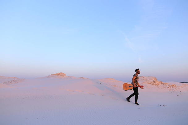 Arab guy goes inspired by beauty of desert and plays guitar stri - Photo, Image