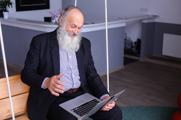 Viejo jubilado utiliza el ordenador portátil y se comunica con sus colegas beh
 - Foto, Imagen