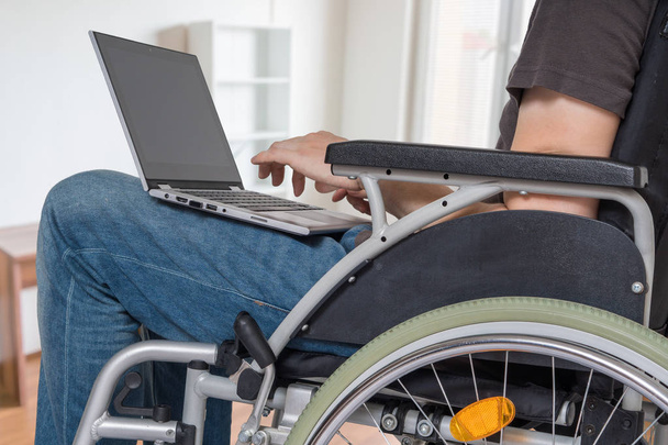 A kerekesszék fogyatékkal élő fogyatékos ember dolgozik a laptop - Fotó, kép