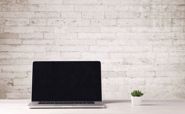 Business laptop with white brick wall - Fotoğraf, Görsel