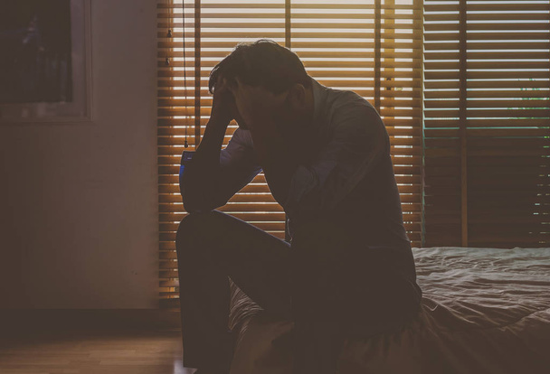 Depresif adam yatakta oturuyor - Fotoğraf, Görsel
