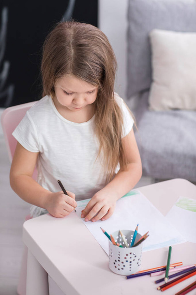 Cute little girl is drawing while spending time at home - Foto, afbeelding