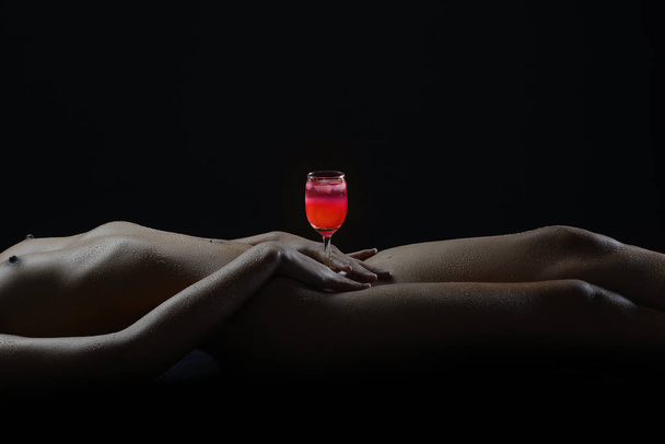 nackte Frau sexy Körper Silhouette Pose wie nackte abstrakte durch Halten rotes Glas auf ihrer Hüfte auf schwarzem Hintergrund. - Foto, Bild