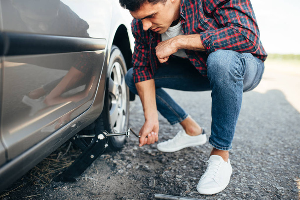 man trying to replace wheel of car - 写真・画像