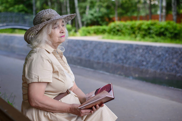 An elderly woman reads a book in the park - Foto, Imagem