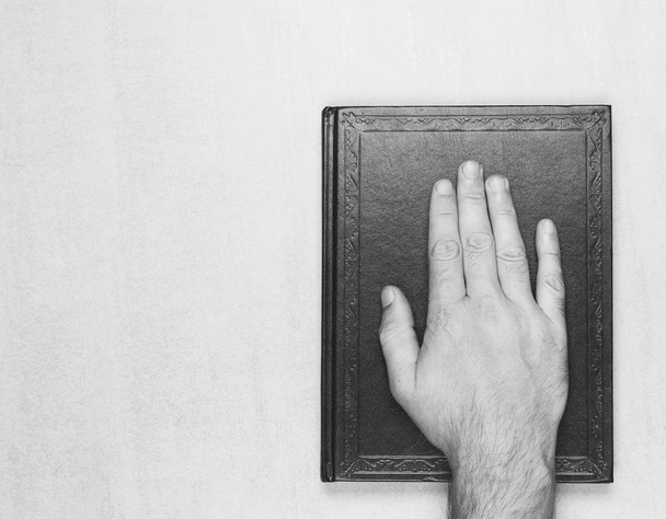 man's hand on the book, the oath on the Bible. top view closeup. black and white photo. mock up for text, phrases, lettering - Foto, Imagem