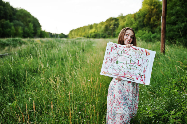 Portrait of a pretty young female artsit holding her painting on - Foto, Imagen