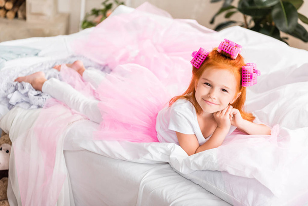 little girl with curlers resting on bed - Foto, Bild