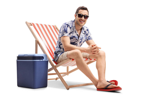 guy sitting in a deck chair next to a cooling box - Fotó, kép