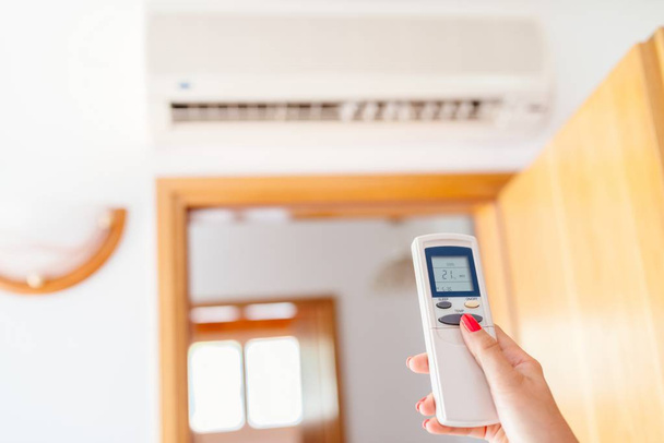 Close up on hand adjusting temperature of home air conditioner - Photo, Image
