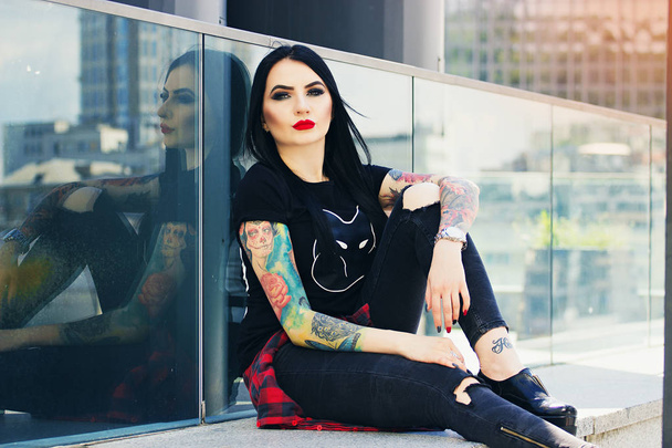 Gorgeous tattoed woman. Portrait of young tattooed hipster girl posing against urban background. - Valokuva, kuva