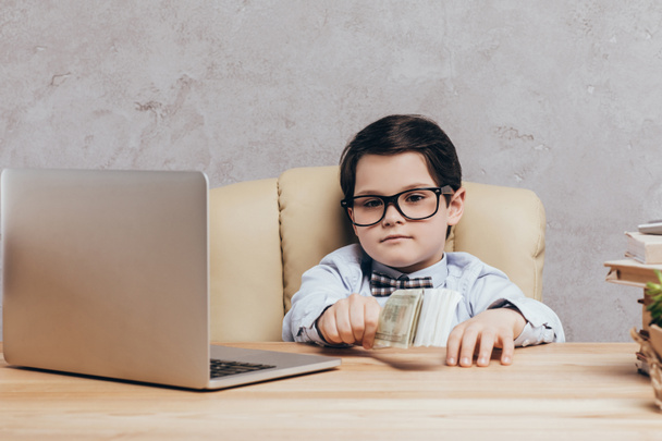 child with cash at workplace with laptop - Foto, Imagem
