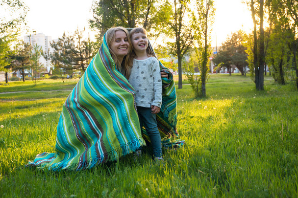Lachen van de jonge moeder en haar dochtertje in een park - Foto, afbeelding