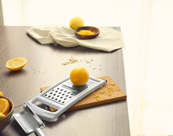 Wooden board with grater and lemon on table - Fotó, kép