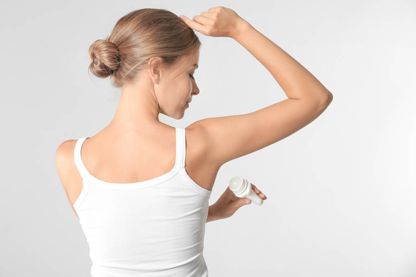 Beautiful young woman with deodorant on light background - Foto, Imagen