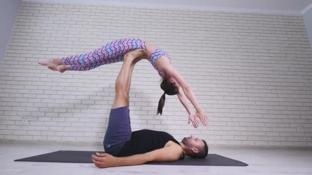 Acrobatic yoga. Young woman and man performing exercises. The combination of acrobatics and yoga - Кадри, відео