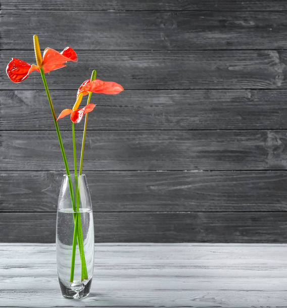 Glass vase with tropical flowers on wooden background - Valokuva, kuva