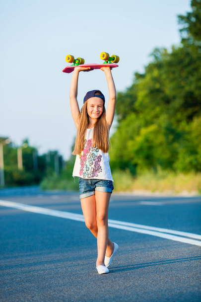 Une jeune fille avec un penny board en dehors de la ville
 - Photo, image