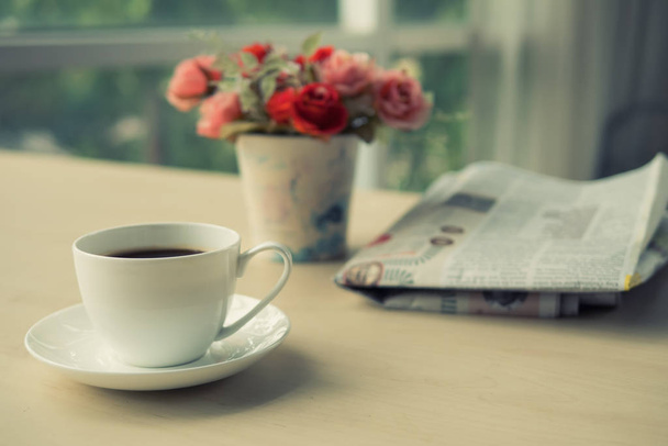Kuppi kahvia sanomalehti pöydällä aamulla, lämmin sävy
 - Valokuva, kuva