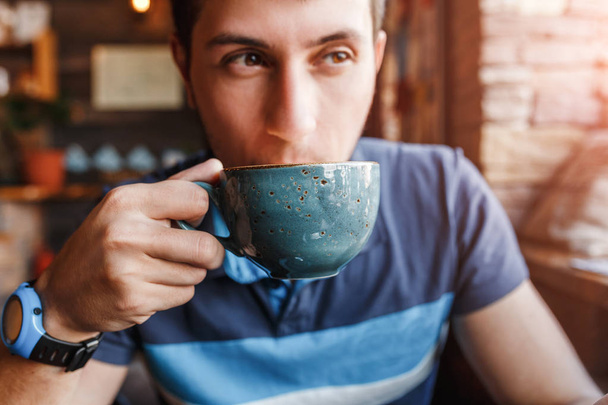 Un joven bebe café aromático en un café o cafetería
 - Foto, imagen