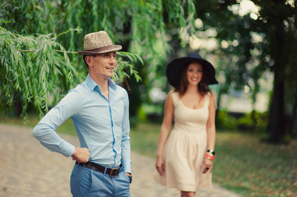Tyttö hattu päässä leveä lieri ja mies kävelyllä puistossa
 - Valokuva, kuva