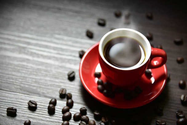 Красная чашка кофе с дымом и кофейных зерен на деревянный стол текстуры, избирательный фокус на край чашки, питьевая концепция, Расслабьтесь концепции
 - Фото, изображение