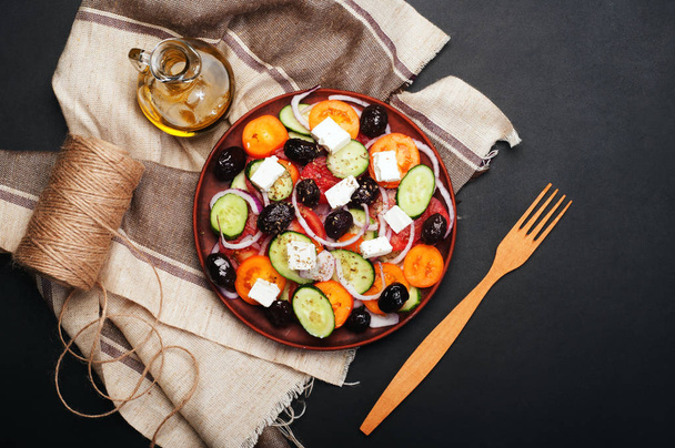 Mediterranean cuisine. Salad from tomatoes, cucumbers, purple onions and dried olives on a brown plate on a dark background. Fusion Greek salad. Tasty and healthy seasonal dish. - Foto, Imagem