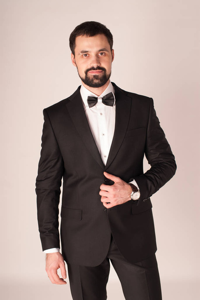 Elegance and style. Portrait of handsome young man wearing tuxedo and red tie. - Photo, Image