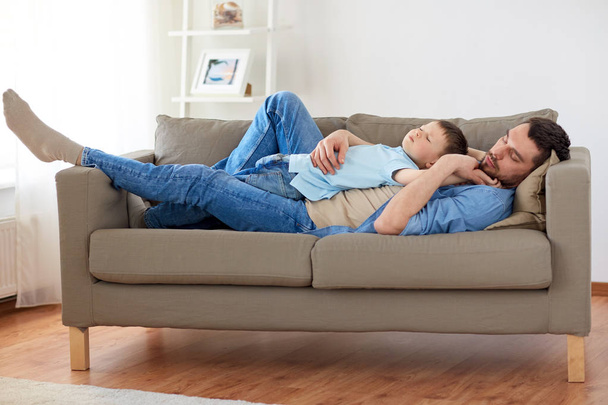 happy father and son sleeping on sofa at home - Φωτογραφία, εικόνα