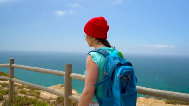 Žena s batohem jde na malebném kopcovitém terénu do oceánu - Záběry, video
