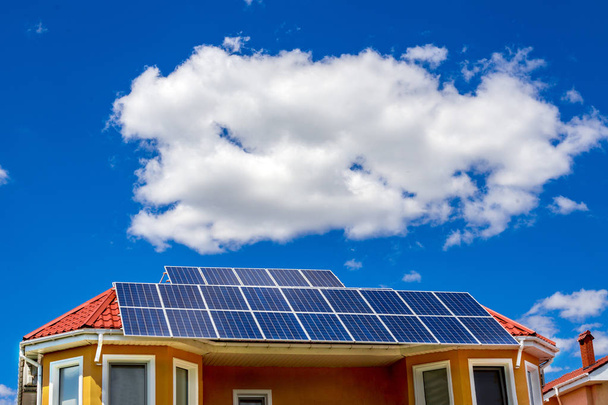 Solární panel na červenou střechou, odrážející slunce a modrá obloha - Fotografie, Obrázek