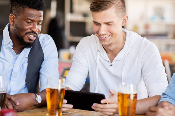 male friends with tablet pc drinking beer at bar - Foto, Bild