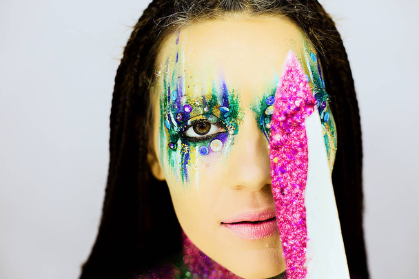 Close up portrait of a beautiful girl with creative glitter make up with knife covered in glitter - Φωτογραφία, εικόνα
