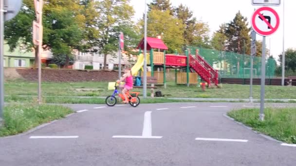Mädchen fährt Fahrrad im Spielplatzverkehr. Kleines Mädchen auf dem Fahrrad im Sommer - Filmmaterial, Video